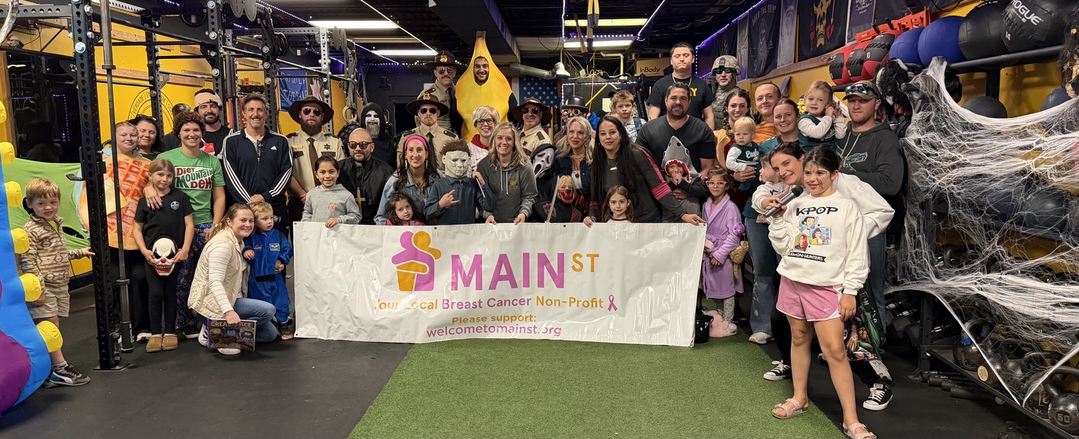Costumed TFW families gathered behind a Welcome to Main St. fundraiser banner at a past Halloween event.